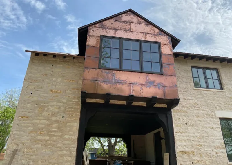 Copper metal panel facade on a stone building for Skylight Installation in Marlene Village